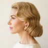 Woman with warm golden 1950s bombshell waves in side profile, smooth wave pattern visible from crown to nape in clean studio light