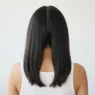 Back view of woman's dark hair freshly center-parted with a rat-tail comb split into two equal loose sections