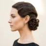 Woman with deep chestnut hair in precise horizontal marcelled waves from crown to nape in matte studio light