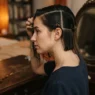 Woman at vintage dressing table with damp hair combed smooth into zones before pin curl setting begins
