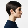 Side profile of woman with sharp mod pixie cut showing precise sideburn line against white studio backdrop