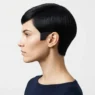 Side profile of woman with sharp sixties mod pixie cut showing razor-clean sideburn line against white backdrop